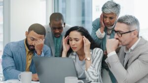 Stressed workers looking at a laptop.